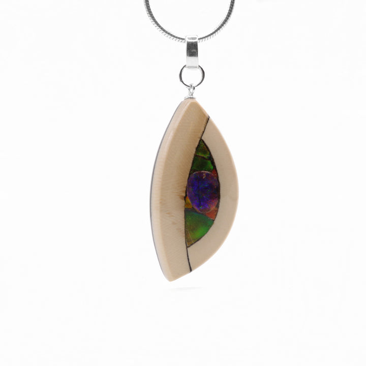 Yuka Ammolite and Mammoth Ivory Pendant handmade by Aryn Bowers. This pendant is double sided with one side containing fossilized mammoth ivory and flakes of the ammolite gemstone and the other fully adorned with flakes of ammolite. The bail is sterling silver.