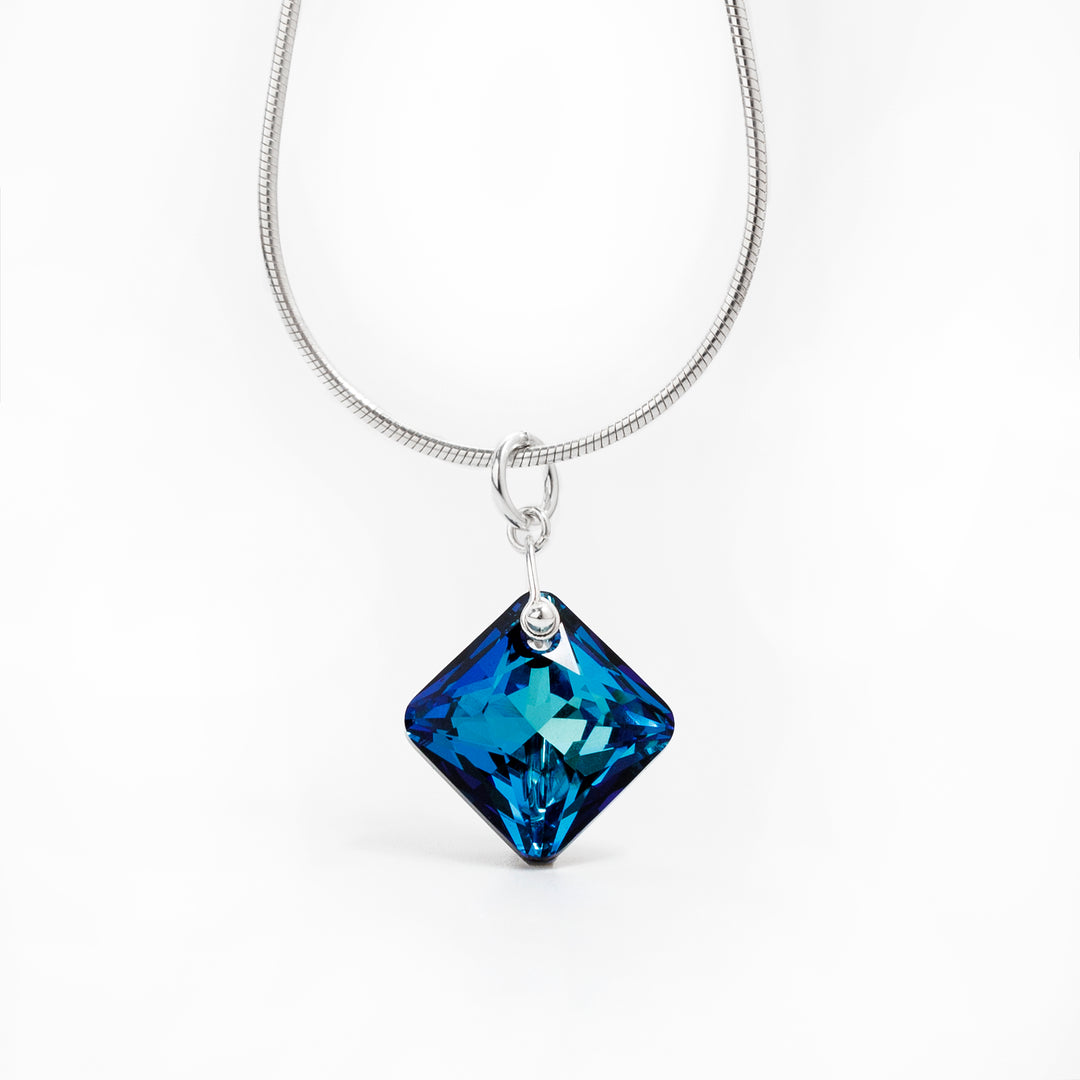 Princess Cut Bermuda Blue Swarovski Crystal Pendant handcrafted by artist Debra Nelson. Made of sterling silver and Bermuda Blue Swarovski Crystal. Pendant measures 1" x 0.63" including bail. Chain not included.