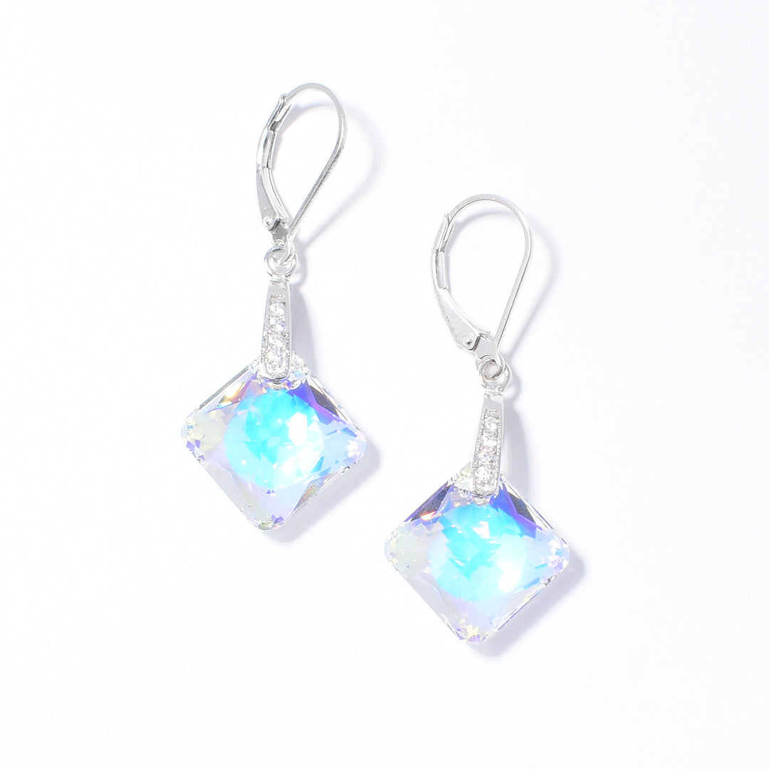 These Swarovski crystal drop earrings are made from sterling silver, cubic zirconia and princess cut Swarovski crystal. The crystals are diamond shaped and hang by coiled, silver wire. The cubic zirconia gems are held between the silver wires of the hangs.