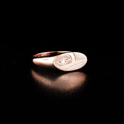 14K rose gold hummingbird signet ring hand-carved by Haisla artist Hollie Bartlett. She has used crosshatching to depict the face of a hummingbird with a diamond set in the eye. Size 5 available.