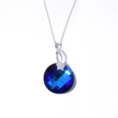 Dazzling round crystal pendant handcrafted by artist Debra Nelson. Pendant made of Bermuda Blue Swarovski Crystal. Sterling silver bail adorned with cubic zirconia. Pendant measures 2" x 1.13" including bail. Chain not included.