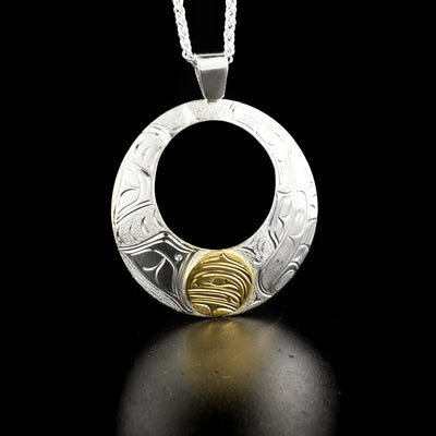 Round cut-out orca pendant hand-carved by Kwakwaka'wakw artist Cristiano Bruno. Made of sterling silver and 14K gold. Pendant measures 2.45" x 2" including bail. Chain not included.