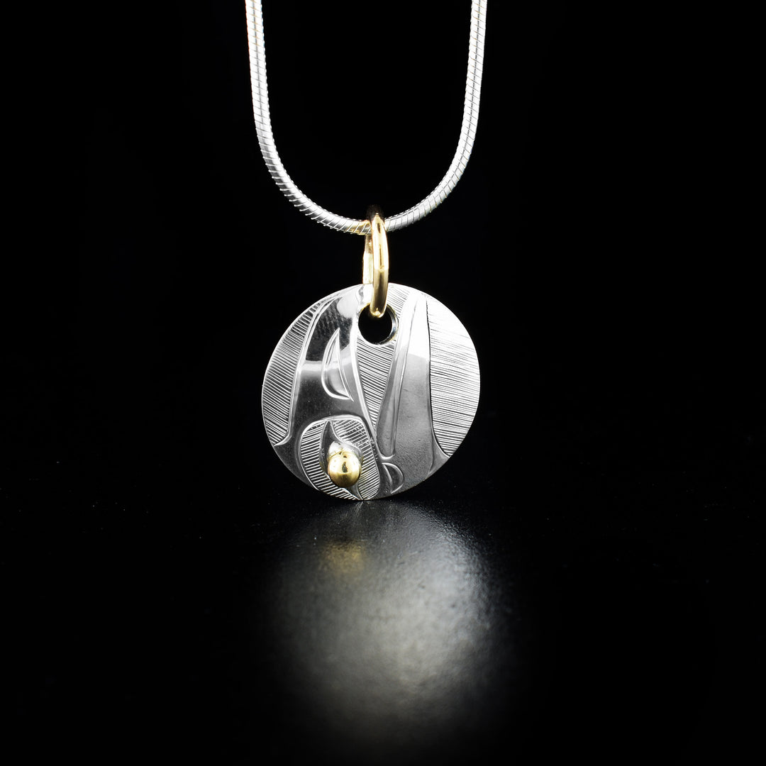 Round Gold and Silver Raven Pendant hand-carved by Haisla artist Hollie Bartlett. She has used sterling silver and 14K gold for this piece. Bail is gold-filled. Pendant measures 0.95" x 0.80" including bail. Chain not included.