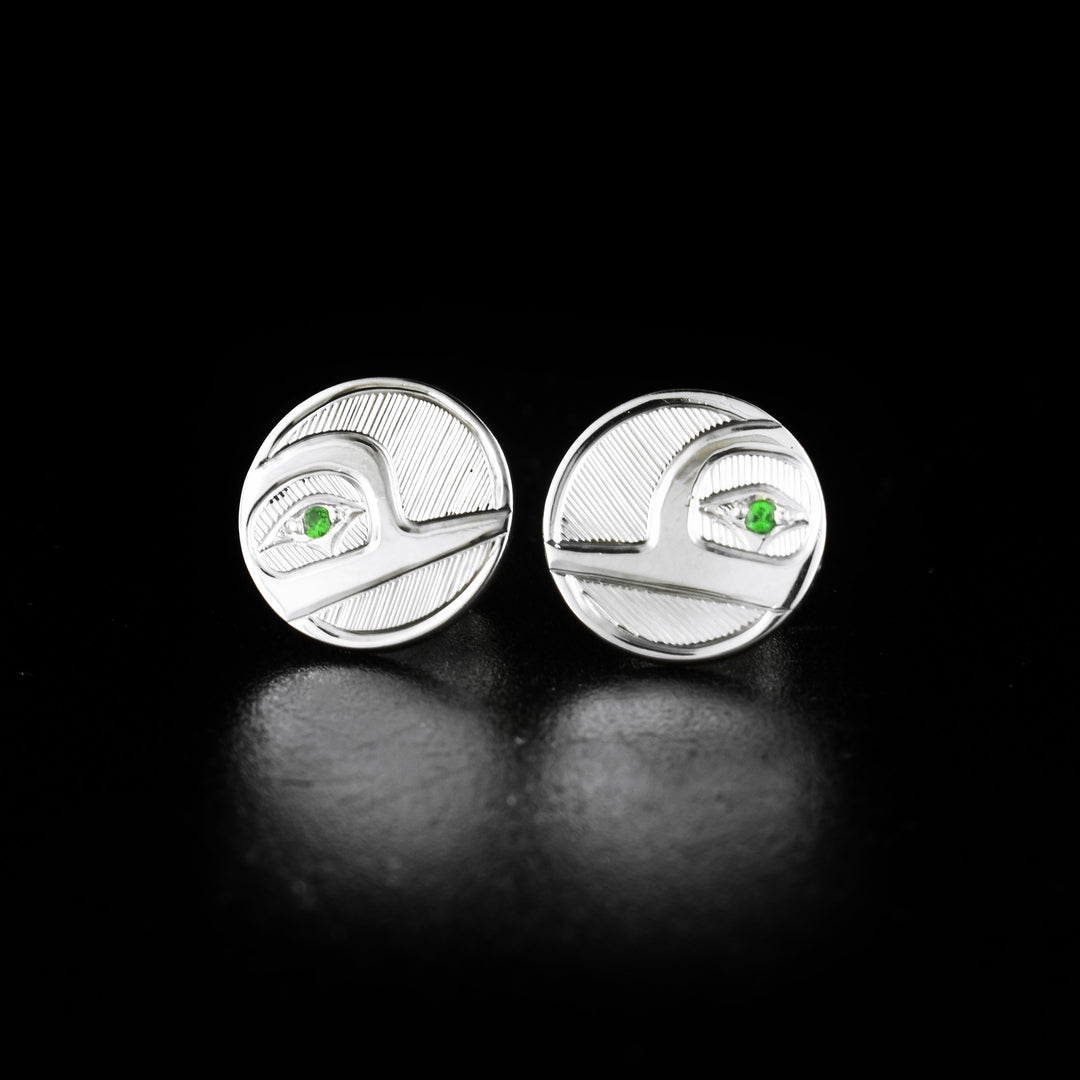Round sterling silver hummingbird stud earrings hand-carved by Haisla artist Hollie Bartlett. She has used sterling silver to create them and set tsavorites in the eyes of the hummingbirds. Each earring is 0.9" in diameter.