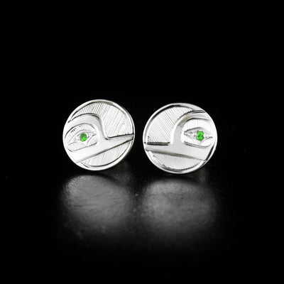 Round sterling silver hummingbird stud earrings hand-carved by Haisla artist Hollie Bartlett. She has used sterling silver to create them and set tsavorites in the eyes of the hummingbirds. Each earring is 0.9" in diameter.