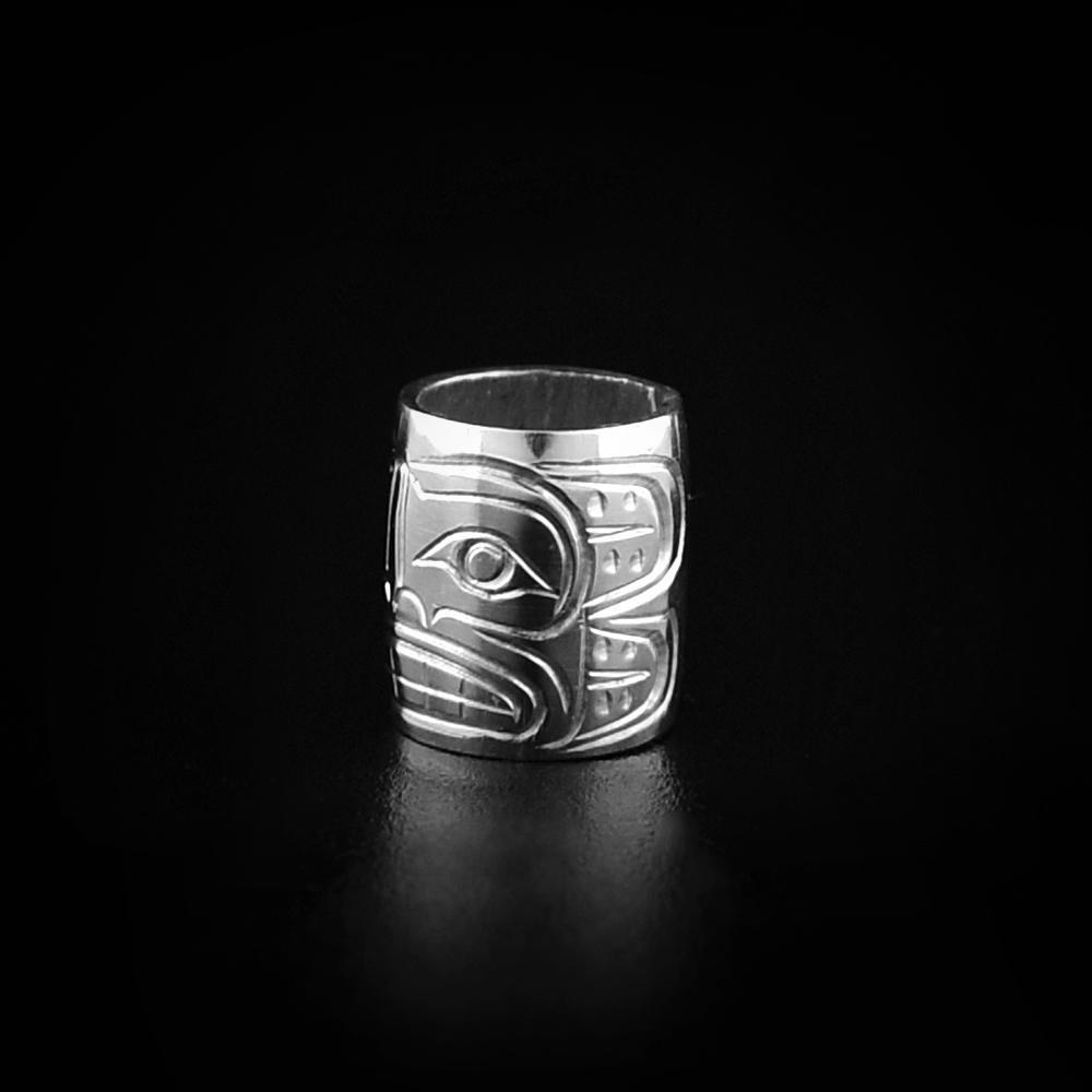 This Sun charm is a bead made from sterling silver and is longer than it is wide. There is a depiction of the Sun carved into the surface of it.