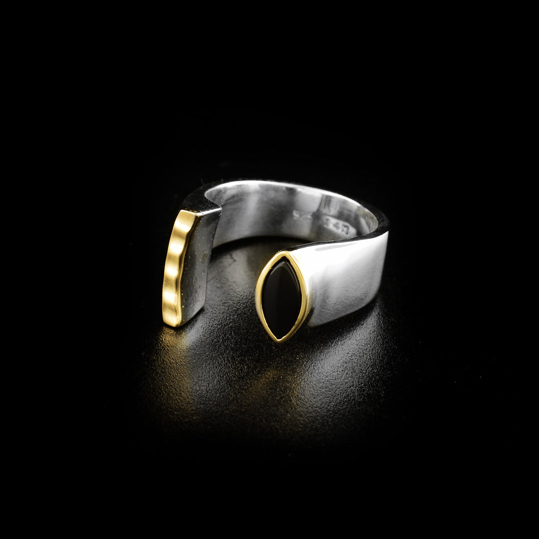 This brilliant black onyx ring is made from sterling silver, 14K gold and black onyx gemstones. The ring has a split in the middle resulting in two signets; one is thing and has a textured, gold highlight, and the other has a gorgeous black onyx gemstone held in gold.