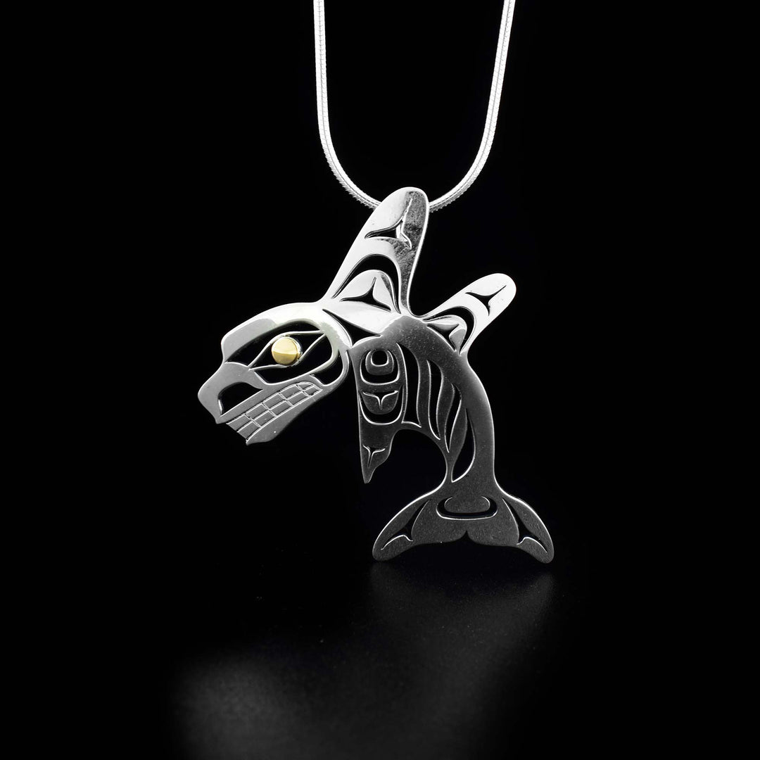 This unique Orca pendant is made from 18K gold and sterling silver. The pendant is shaped like and has cutout designs that depict the Orca with two dorsal fins. The eye of the Orca is made from 18K gold.