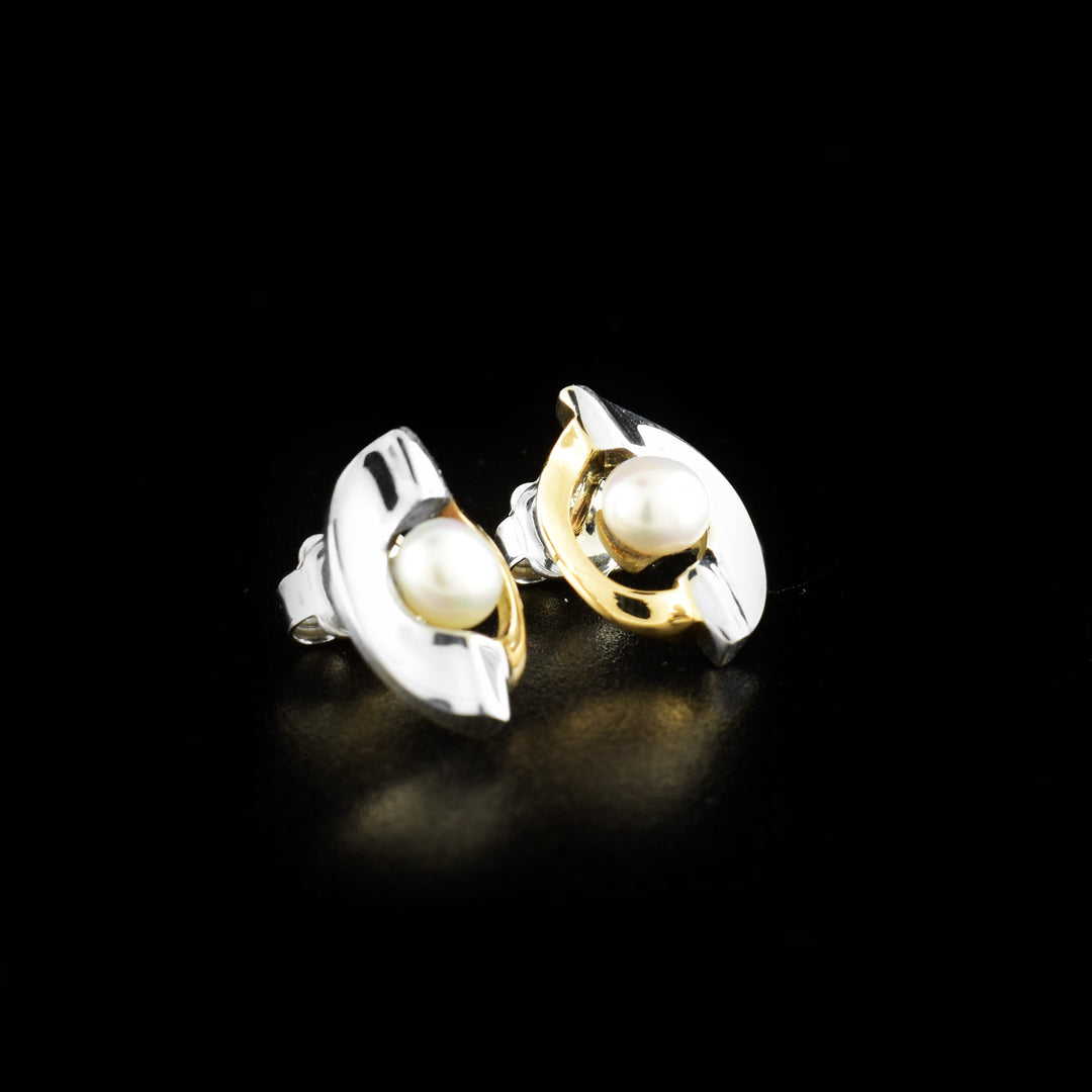 These gold pearl earrings are made from sterling silver, 14K gold and fresh water pearls. The earrings are circles with half silver and gold and a cutout in the center. The pearls have been set in the middle of the cutouts giving them a floating appearance.