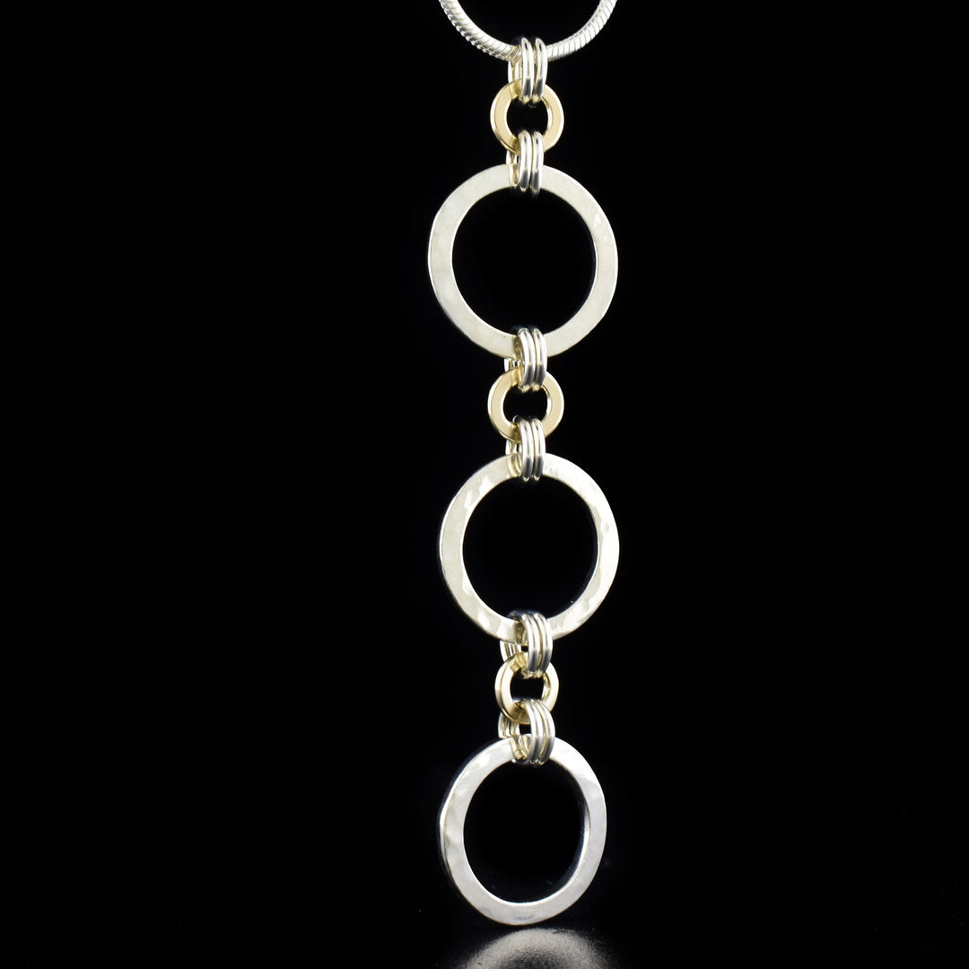 Silver and Gold Kindness Triple Pendant Necklace by artist Lynda Constantine. She has used sterling silver and 14K gold to create the pendant. Sterling silver snake chain included. Chain is 18" long and pendant measures 2.75" x 0.63".