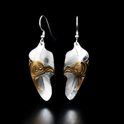 Dazzling eagle head in feather earrings hand-carved by Tlingit artist Fred Myra. He used sterling silver to create them. Eagle heads are done in 18K gold plating. Each earring measures 2" x 0.63" including hook.