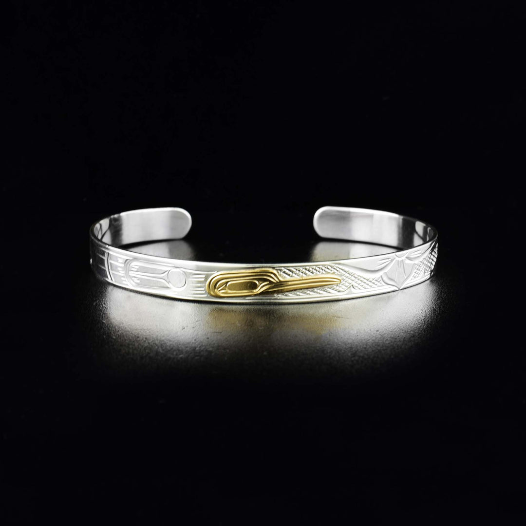 This Hummingbird bracelet is made from sterling silver and 14K gold. It has a thin band with a gap in the back. There is a depiction of the Hummingbird carved into the band and the head of the Legend is made from 14K gold.