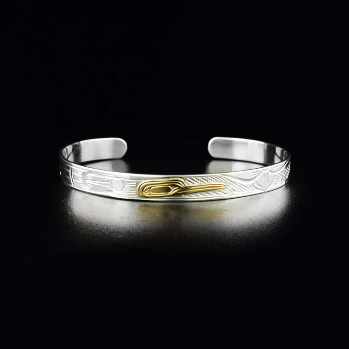 This Hummingbird bracelet is made from sterling silver and 14K gold. It has a thin band with a gap in the back. There is a depiction of the Hummingbird carved into the band and the head of the Legend is made from 14K gold.