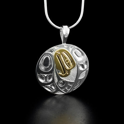 Dazzling round eagle pendant hand-carved by Indigenous artist Ivan Thomas. Made of sterling silver and 14K gold. Pendant measures 1.38" x 1.10" including bail. Chain not included.