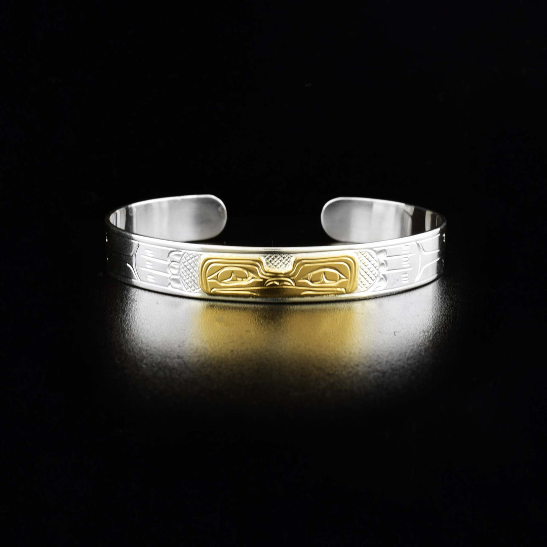 This Frog bracelet is made from sterling silver, 14K gold and has a single band with a gap in the back. There is a depiction of the Frog carved into the surface of the band and the head of the legend is made from gold.