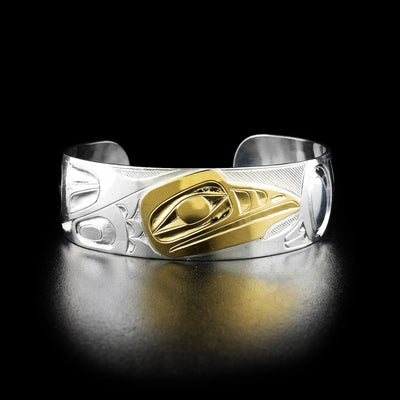 Raven cuff bracelet hand-carved by Indigenous artist Ivan Thomas. Made of sterling silver and 14K gold. Bracelet is 6.19" long with 1.13" gap and has width of 0.75".