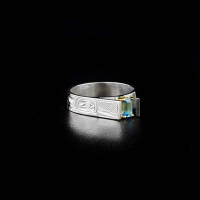 Dazzling Silver and Gold Topaz Hummingbird Ring hand-carved by Tlingit artist Fred Myra. The blue topaz is set in 14K gold and the ring is sterling silver. Topaz measures 5 mm x 3 mm. Size 7.