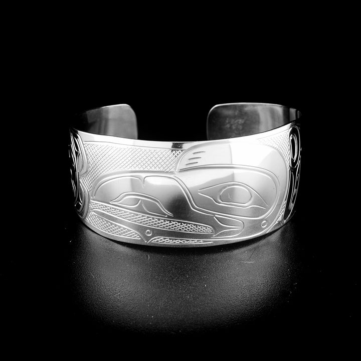 Tapered raven and sun bracelet hand-carved by Kwakwaka'wakw artist John Lancaster. Made of sterling silver. Bracelet is 6.15" long with 0.80" gap and has width of 1". Tapered ends.