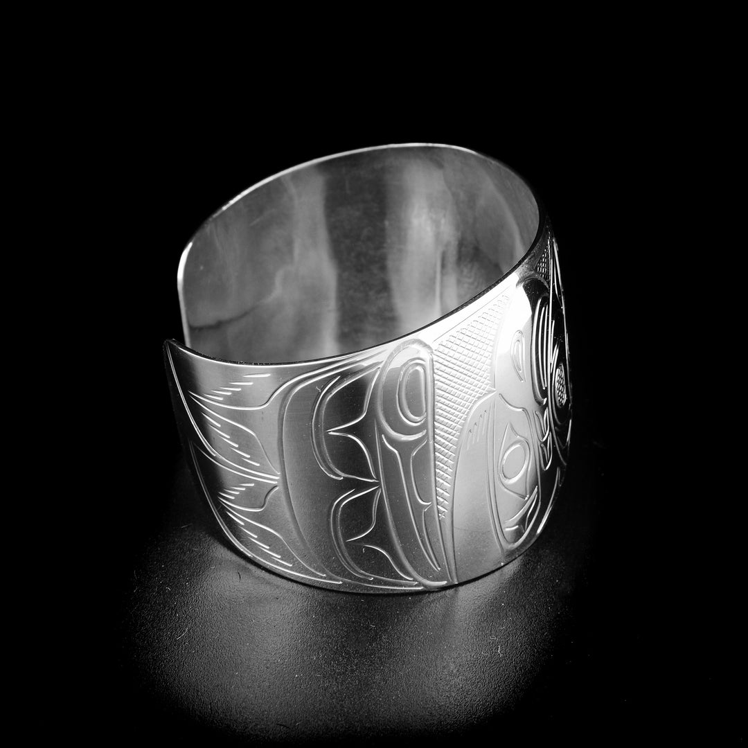Eagle, moon and raven bracelet hand-carved by Kwakwaka'wakw artist John Lancaster. Made of sterling silver. Bracelet is 6.20" long with 0.85" gap and has width of 1.50". Tapered ends.