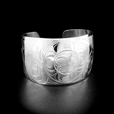 Eagle, moon and raven bracelet hand-carved by Kwakwaka'wakw artist John Lancaster. Made of sterling silver. Bracelet is 6.20" long with 0.85" gap and has width of 1.50". Tapered ends.
