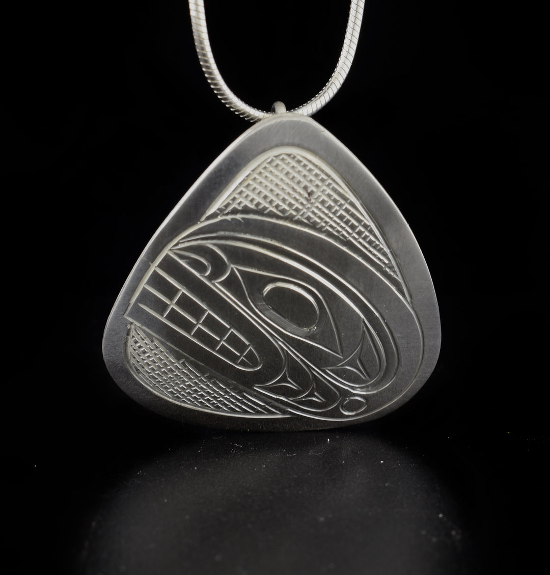 This Orca pendant is made using sterling silver and has a rounded triangle shape. There is a depiction of the Orca that has been beautifully carved into the surface of the piece and there is cross hatching design textures on the negative space.