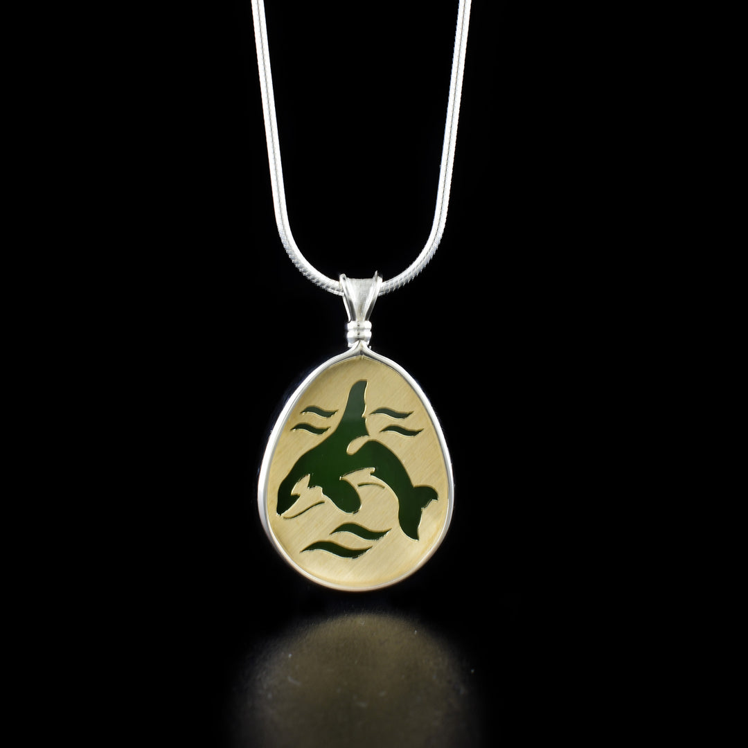 This orca pendant is made using sterling silver, 14K gold and grade A+ BC jade. There is a depiction go the orca hand carved into a gold plate which is backed on the jade. The piece is held together by a silver band running along the edge and included the bail.