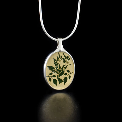 Small BC Jade Hummingbird Flight Pendant handcrafted by artist Dennis Kangasniemi. He engraves his original designs on 14K yellow gold panels. The panels are then soldered in heavy sterling silver pendant settings and finished with a backdrop of A+ grade BC jade. The artist achieves his BC wildlife jewellery by precise hand-cutting. Pendant measures 1.25" x 0.75" including bail. Chain not included.