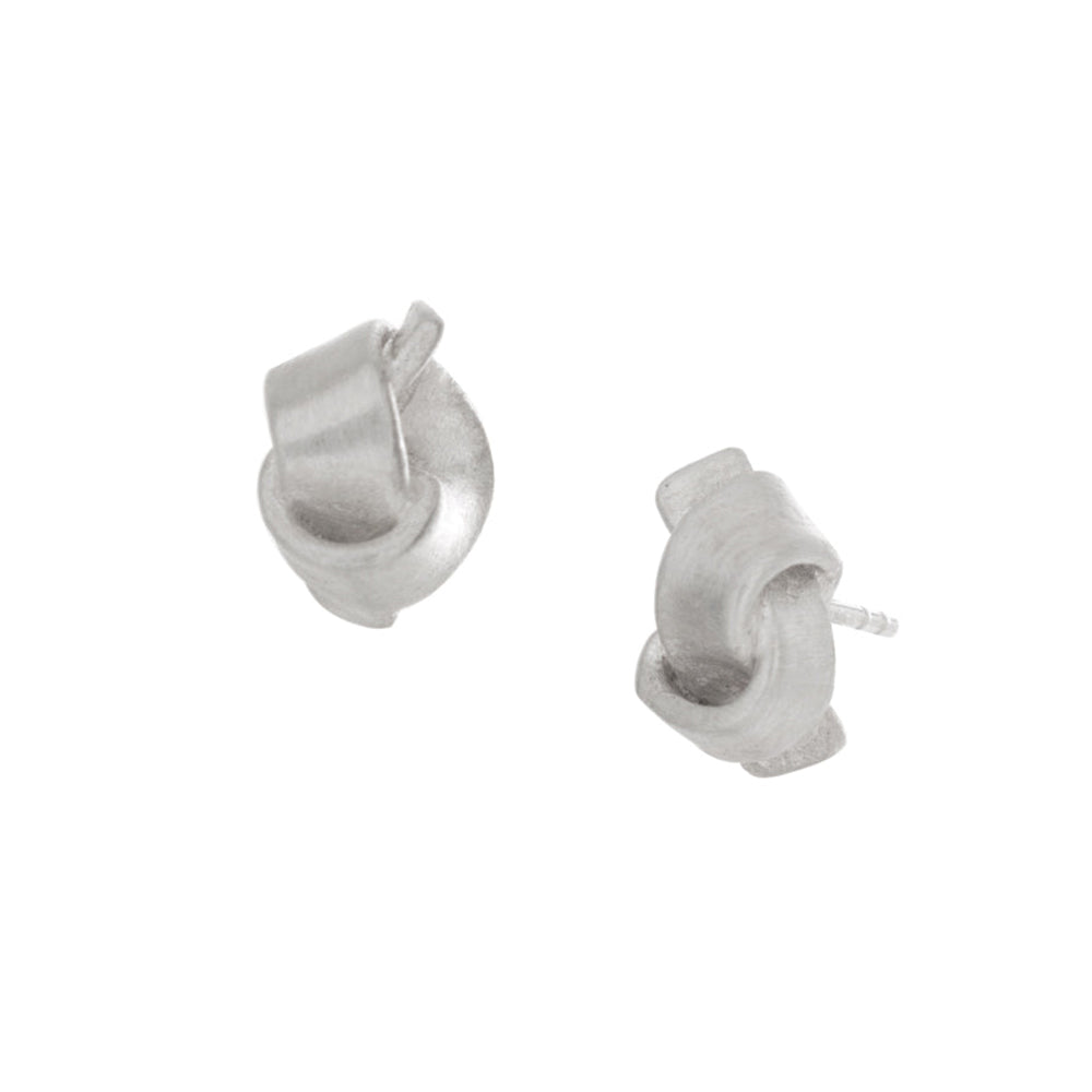 These love knot earrings are made from sterling silver and have a round shape. The studs are shaped like simple knots and have a satin texture on the surface of them.