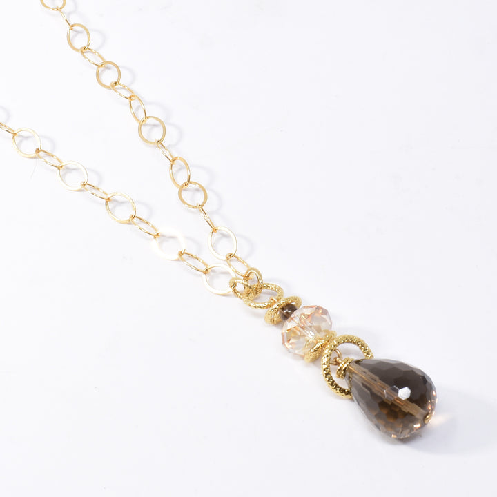 Swarovski Crystal smoky quartz pendant necklace handcrafted by artist Karley Smith. Pendant made of gold-plated adornments and wire, smoky quartz and a Swarovski crystal in Golden Shadow. Chain is gold-filled. Pendant measures 2.15" x 0.65" and chain is 24" long.