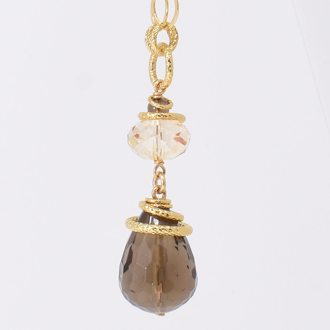 Smoky Quartz and Swarovski Crystal Pendant Necklace handcrafted by artist Karley Smith. Pendant made of gold-plated adornments and wire, smoky quartz and a Swarovski crystal in Golden Shadow. Chain is gold-filled. Pendant measures 2.15" x 0.65" and chain is 24" long.