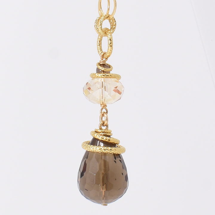 Smoky Quartz and Swarovski Crystal Pendant Necklace handcrafted by artist Karley Smith. Pendant made of gold-plated adornments and wire, smoky quartz and a Swarovski crystal in Golden Shadow. Chain is gold-filled. Pendant measures 2.15" x 0.65" and chain is 24" long.