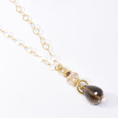 Smoky Quartz and Swarovski Crystal Pendant Necklace handcrafted by artist Karley Smith. Pendant made of gold-plated adornments and wire, smoky quartz and a Swarovski crystal in Golden Shadow. Chain is gold-filled. Pendant measures 2.15" x 0.65" and chain is 24" long.