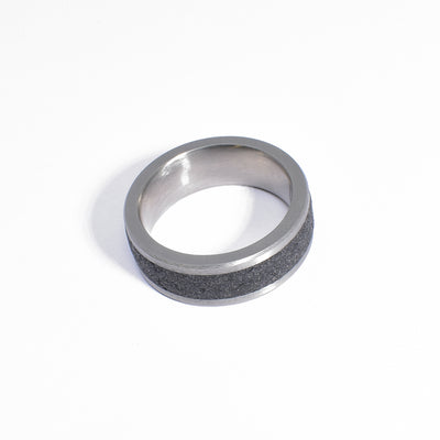 Ring is made of stainless steel. There is an even diamond dust-infused concrete strip all the way across. 0.25” band width.