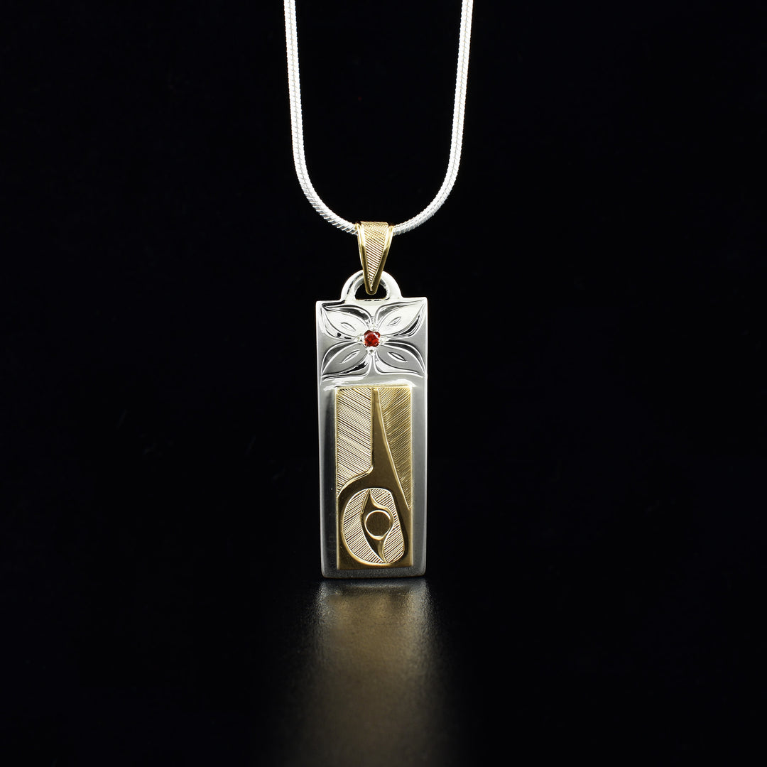 Sterling silver and 14K gold hummingbird pendant with garnet hand-carved by Haisla artist Hollie Bartlett. Pendant measures 1.63" x 0.50" including bail. Chain not included.