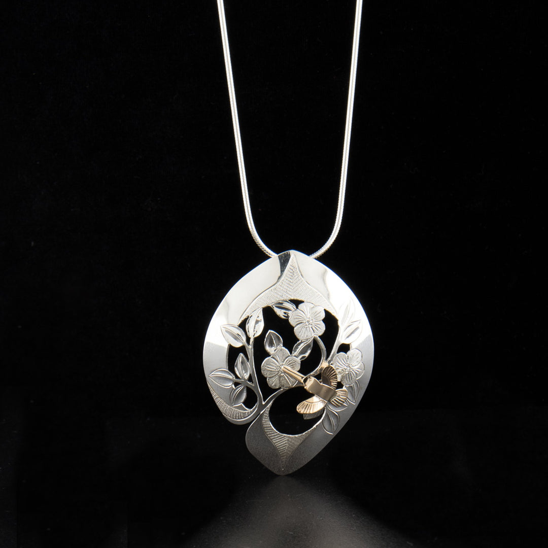 Sterling silver and 14K gold hummingbird and roses pendant hand-carved by artist Arlene Howk. Pendant measures 2" x 1.50". Hidden bail on back. Chain not included.