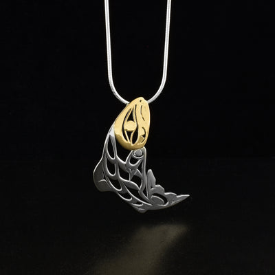 Pierced salmon pendant by Tahltan artist Grant Pauls. He has used 18K gold for the face of the salmon and sterling silver for the rest of the piece. Pendant measures 1.75" x 0.69". Hidden bail on back. Chain not included.