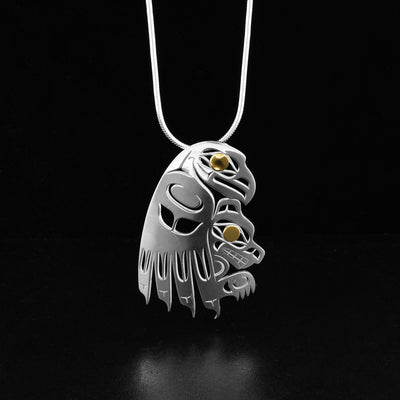 Wolf and eagle pendant by Tahltan artist Grant Pauls. He has used sterling silver to create this piece and accented the eye of the wolf and the eye of the eagle with 18K gold. Pendant measures 1.75" x 1.13". Hidden bail on back. Chain not included.