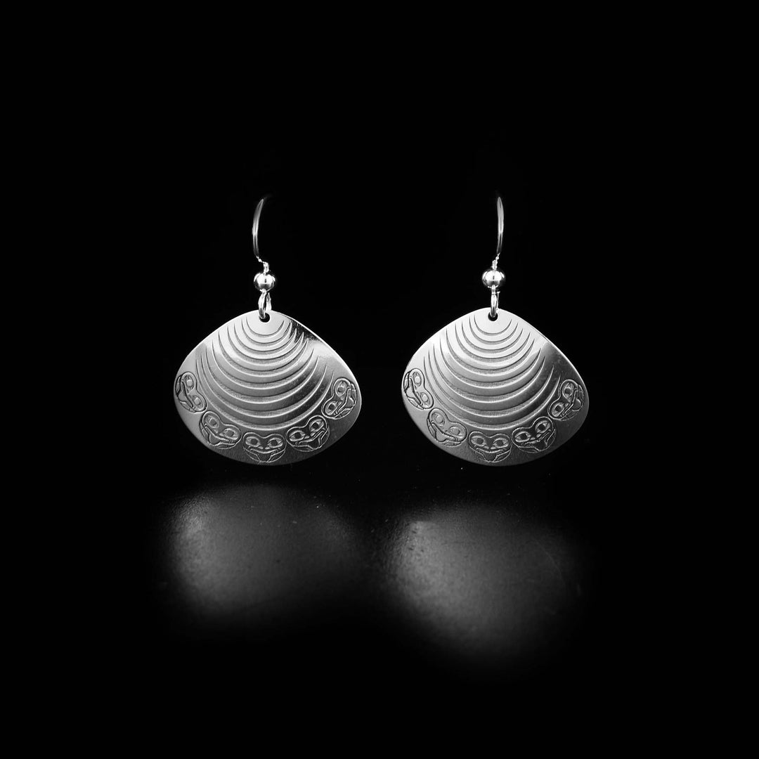 These Clam and Frog earrings are made from sterling silver and have oval shaped hangs. The hangs are shaped like and have carving depicting the Clam and there are carvings of the Frog around the bottom.