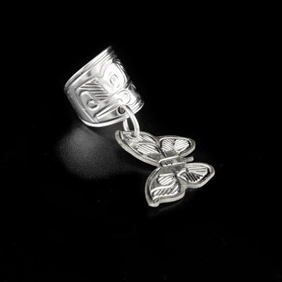 Ear cuff hand-carved by Heiltsuk artist Ivan Wilson. Made of sterling silver. There is an eagle carved into the cuff and the dangling adornment is a butterfly. Ear cuff is 1.50" long including butterfly and cuff is 0.44" wide.