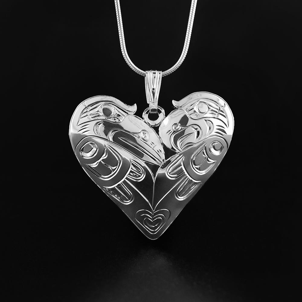 This Raven and Eagle pendant is made from sterling silver and is heart shaped. There are depictions of the Eagle and the Raven cast into the pendant, and they are depicted embracing in a heart shape.