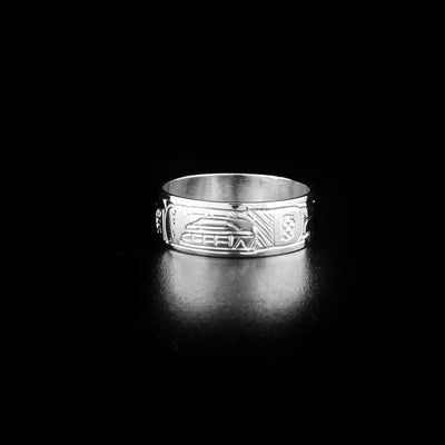 Sterling Silver 5/16" Orca Ring by Jeffrey Pat. In the center of the ring is the profile of an orca's face facing towards the right. The orca has an open mouth showing its sharp teeth. The artist has hand-carved intricate designs along the rest of the ring that represent the orca's body and fins.
