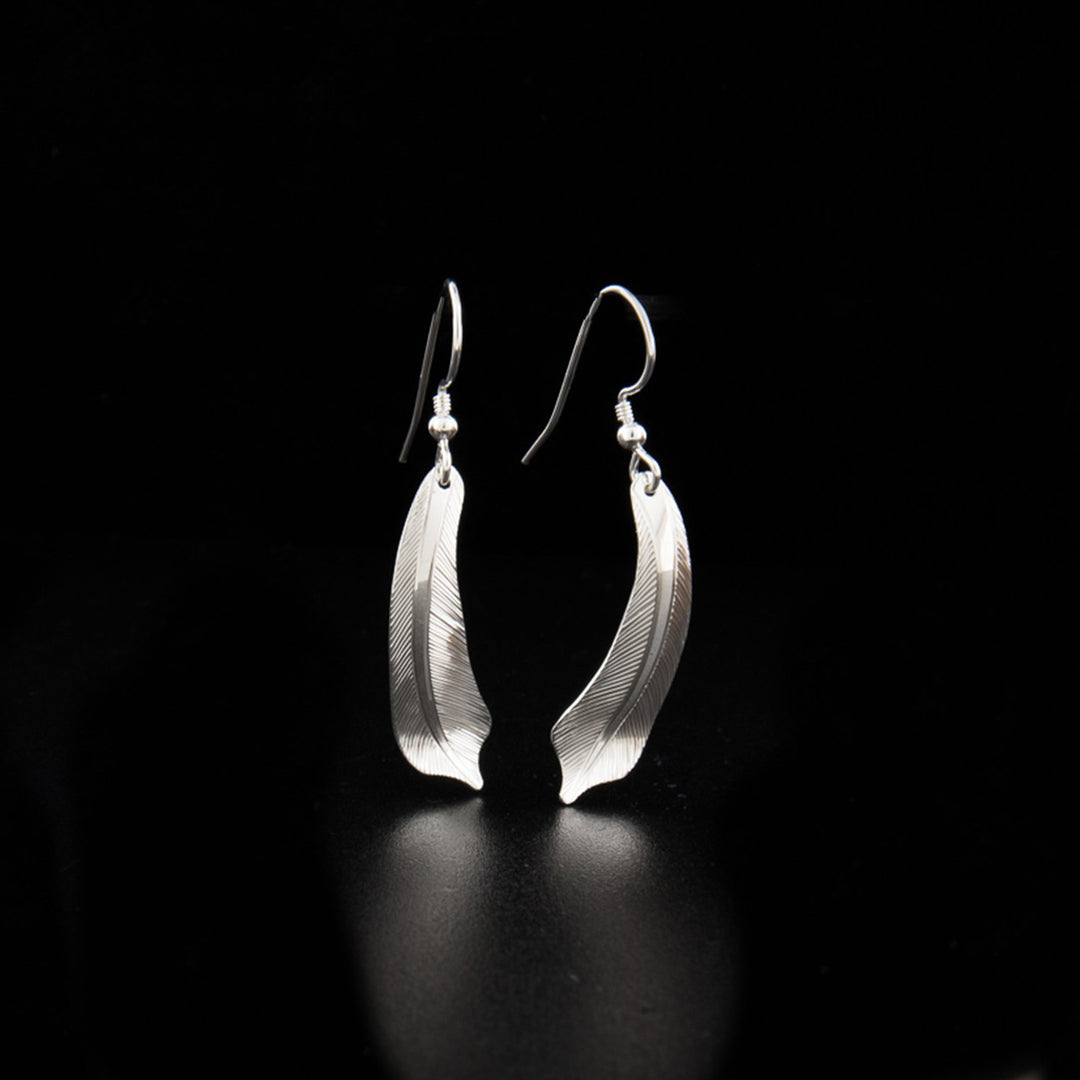 Sterling silver flicker feather earrings hand-carved by Tlingit artist Fred Myra. Each earring measures 1.75" x 0.38" including hook.
