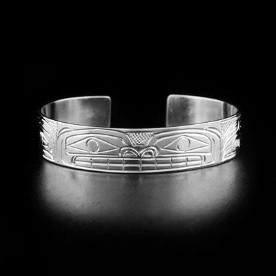 Bear bracelet hand-carved by Heiltsuk artist Reg Gladstone. Made of sterling silver. Bracelet is 6" long with 0.9" gap and has width of 0.5".