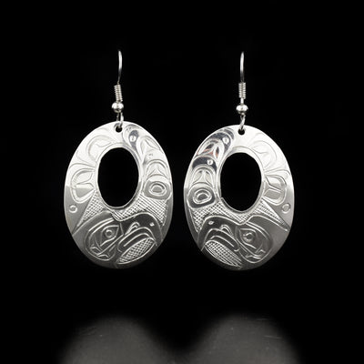Sleek oval cut out eagle earrings hand-carved by Kwakwaka'wakw artist Don Lancaster. Made of sterling silver. Each earring measures 2" x 1" including hook.
