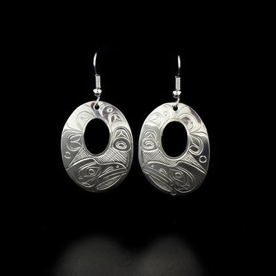 Sleek oval raven cut out earrings hand-carved by Kwakwaka'wakw artist Don Lancaster. Made of sterling silver. Each earring measures 2" x 1" including hook.