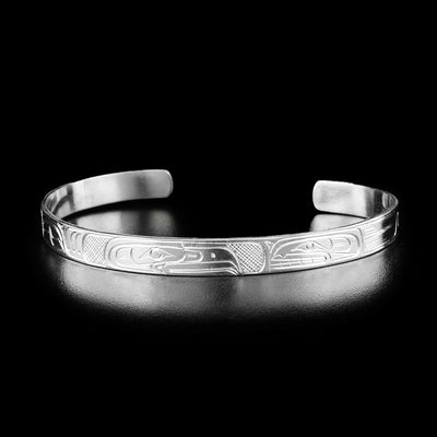 This cuff bracelet has the profile of an eagle's head in the center facing towards the head of an orca.