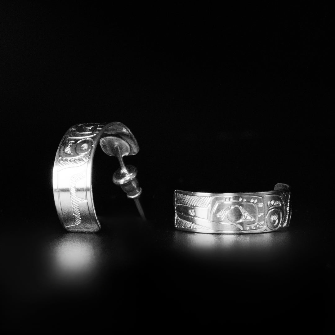 These wide hoop earrings are made from sterling silver and has band curved back into a hoop with a gap in the back. There are depictions of the Hummingbird carved into the surface of the band.