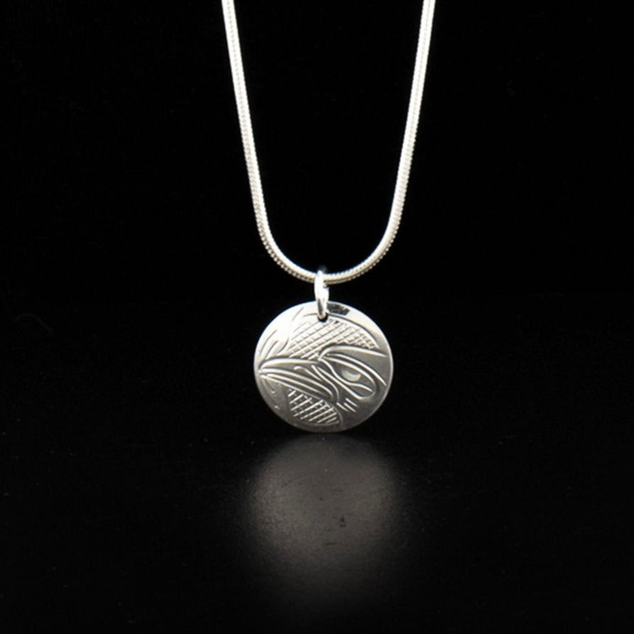 Sterling silver raven charm pendant hand-carved by Kwakwaka'wakw artist John Lancaster. Pendant measures 0.75" x 0.63" including bail. Chain not included.