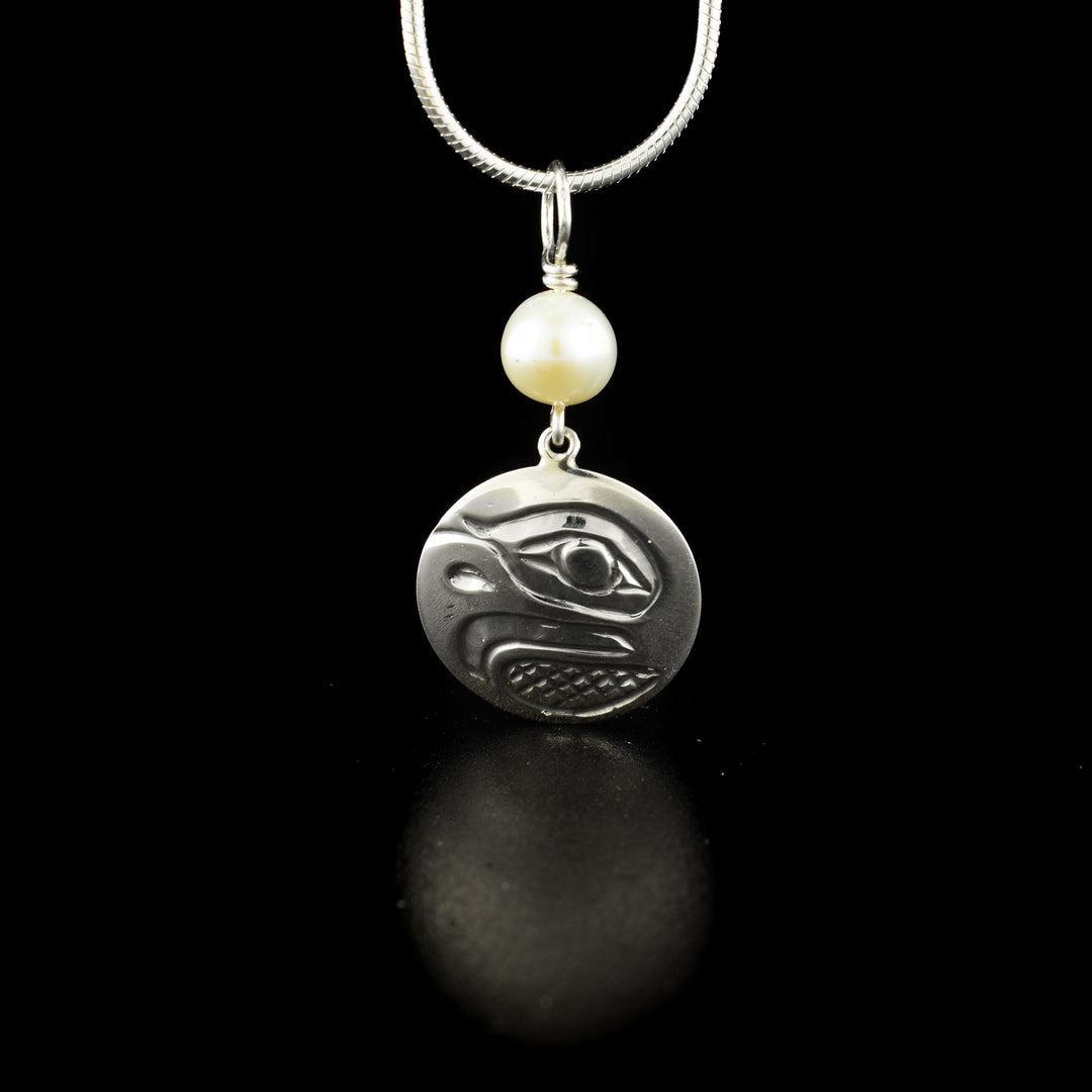 Round eagle pendant with pearl hand-carved by Kwakwaka'wakw artist Carrie Matilpi. Made of sterling silver and freshwater pearl. Pendant measures 1" x 0.60" including bail. Chain not included.