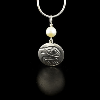Round eagle pendant with pearl hand-carved by Kwakwaka'wakw artist Carrie Matilpi. Made of sterling silver and freshwater pearl. Pendant measures 1" x 0.60" including bail. Chain not included.